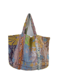 Flerfarvet broderet patchwork-tote-taske med blomstermønstre og quiltet tekstildesign på hvid baggrund